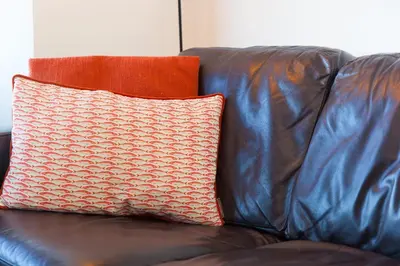a brown leather couch with a pillow on it at Oystercatcher House in St Ives