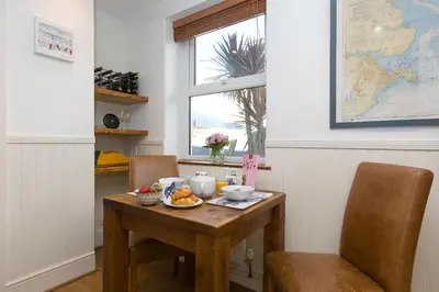 a table with a plate of food on it in a room with a window at Oystercatcher House in St Ives