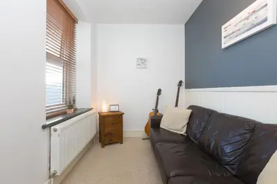 a living room with a leather couch and a guitar at Oystercatcher House in St Ives