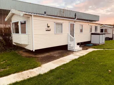 a white house with a porch and a yard at 69 Newquay bay resort Pet friendly in Newquay
