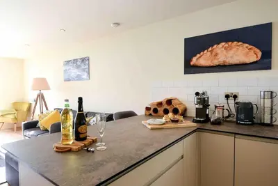 a kitchen with a counter with bottles of wine and a loaf of bread at Fishermans Heights in Polperro