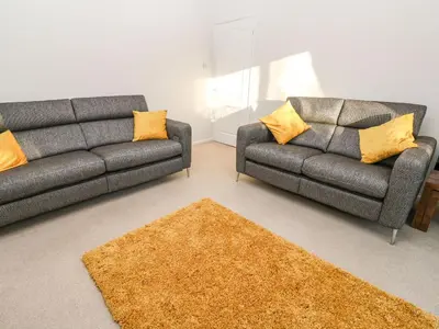 a living room with two couches and a rug at Dunes View in Newquay