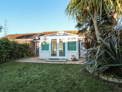 a white conservatory with a dog in a yard at Dunes View in Newquay