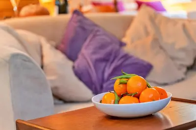 a bowl of oranges on a table on a couch at Finest Retreats - Jenny Wren in Boscastle