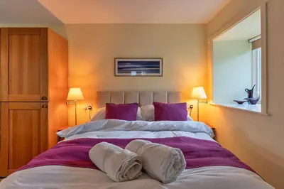 a bedroom with two beds with purple and white pillows at Finest Retreats - Jenny Wren in Boscastle