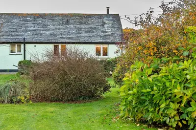 a white house with a gray roof and some bushes at Finest Retreats - Jenny Wren in Boscastle