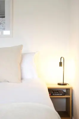 a white bed with a nightstand next to a bed sidx sidx sidx at The Palm House Falmouth - minutes from the beach! in Falmouth