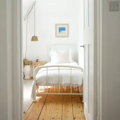 a bedroom with a white bed and a wooden floor at The Palm House Falmouth - minutes from the beach! in Falmouth