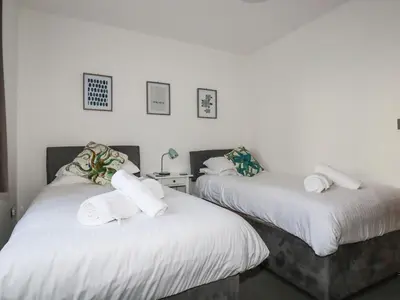 two beds in a room with white sheets and towels at Flat 4 in Newquay