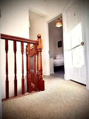 a hallway with a wooden staircase and a bedroom at The White House at The Tinners Arms in St Ives