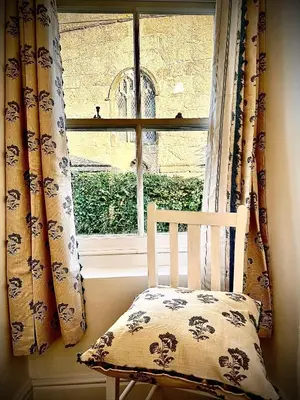 a chair sitting in front of a window with a pillow at The White House at The Tinners Arms in St Ives