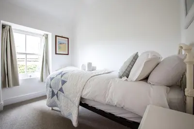 a white bed with white pillows and a window at The White House at The Tinners Arms in St Ives