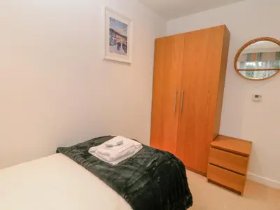 a bedroom with a bed and a wooden cabinet at A Stone's Throw in Torpoint