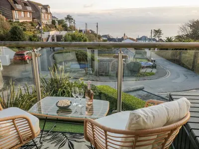 a balcony with a table and two glasses of wine at A Stone's Throw in Torpoint