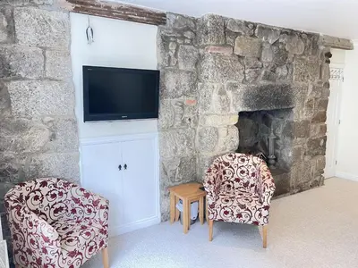 a living room with two chairs and a stone fireplace at Penryn in St Ives