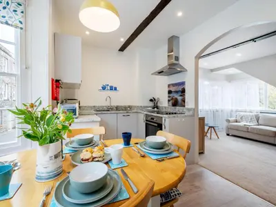 a kitchen and living room with a wooden table and a dining room at Holiday Home Cherry Orchard Cottage by Interhome in Mevagissey