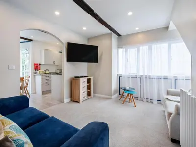 a living room with a blue couch and a tv at Holiday Home Cherry Orchard Cottage by Interhome in Mevagissey