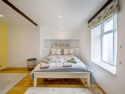 a white bedroom with a bed with a window at Holiday Home Cherry Orchard Cottage by Interhome in Mevagissey