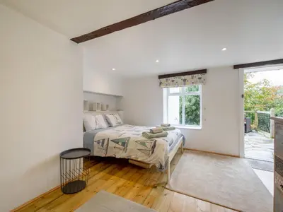 a white bedroom with a bed and a window at Holiday Home Cherry Orchard Cottage by Interhome in Mevagissey