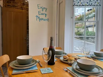 a dining room table with a bottle of wine and glasses at Holiday Home Cherry Orchard Cottage by Interhome in Mevagissey