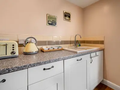 a kitchen with white cabinets and a sink at Holiday Home Cherry Orchard House by Interhome in Mevagissey