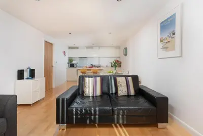 a living room with a black leather couch with pillows at 22 Zinc in Newquay