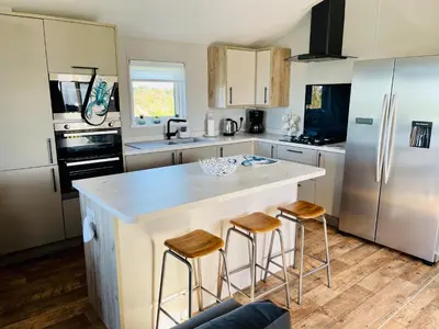 a kitchen with a large island with bar stools at C-Scape Lodge in Newquay