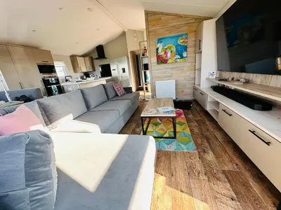 a living room with a couch and a kitchen at C-Scape Lodge in Newquay