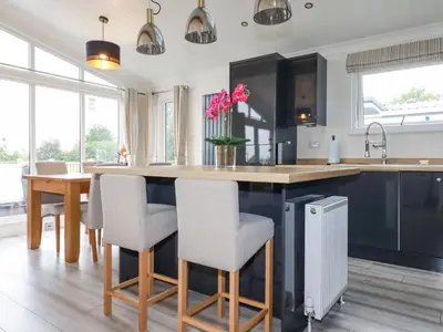 a kitchen with a counter with chairs and a table at Mordros Lodge in Redruth