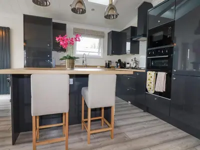 a kitchen with black cabinets and a kitchen island with two chairs at Mordros Lodge in Redruth