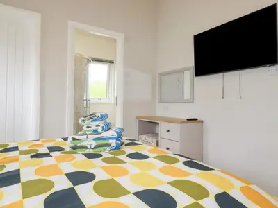 a bedroom with a bed and a flat screen tv at Mordros Lodge in Redruth