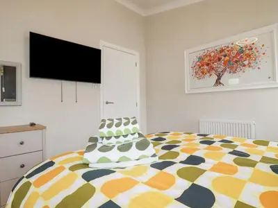 a bedroom with a bed and a flat screen tv at Mordros Lodge in Redruth