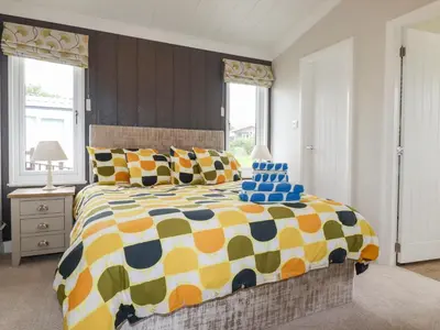 a bedroom with a large bed with colorful pillows at Mordros Lodge in Redruth