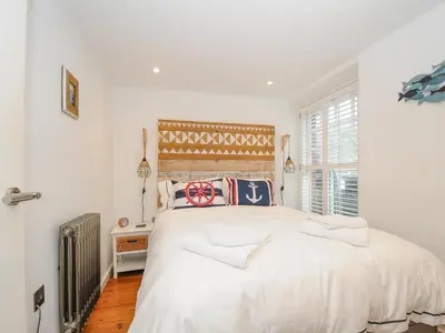 a white bedroom with a large bed and a window at Salty Sea Dog in Tintagel