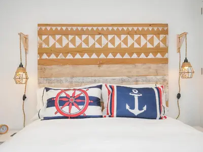 a bedroom with a white bed with a wooden headboard at Salty Sea Dog in Tintagel
