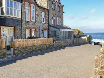 a building on the beach with the ocean behind it at Salty Sea Dog in Tintagel