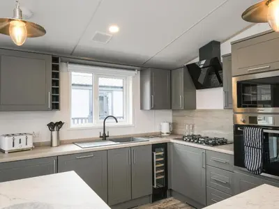 a kitchen with gray cabinets and a sink at Penmarlam Lodge Retreat 18 in Fowey