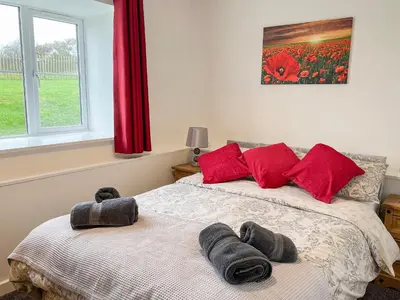 a bedroom with a bed with two towels on it at Four Burrows Bungalow in Chacewater