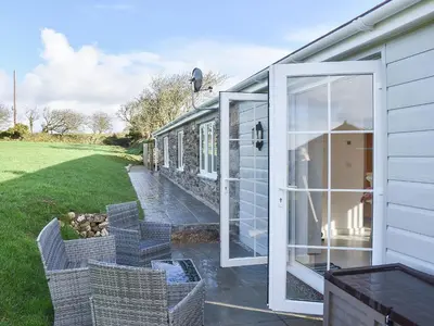 an open door to a house with chairs outside at Four Burrows Bungalow in Chacewater