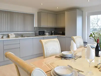 a kitchen with a wooden table with chairs and a dining room at Four Burrows Bungalow in Chacewater
