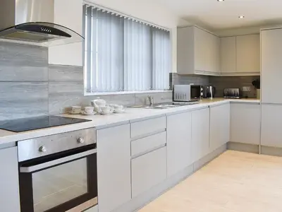 a white kitchen with white cabinets and a window at Four Burrows Bungalow in Chacewater
