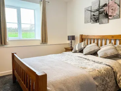 a bedroom with a large bed and a window at Four Burrows Bungalow in Chacewater