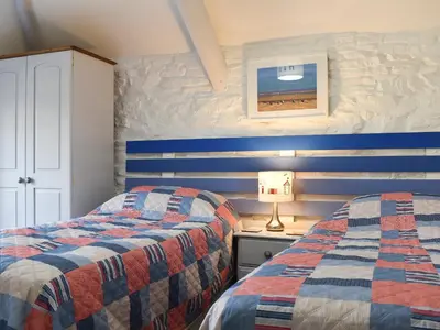 two beds in a bedroom with blue and white stripes at Appleloft in Saint Gennys
