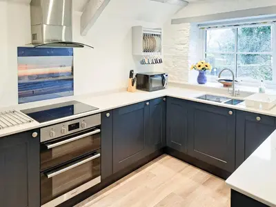 a kitchen with black cabinets and a sink at Appleloft in Saint Gennys