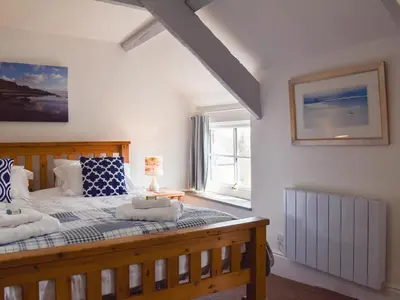 a bedroom with a large wooden bed with a window at Appleloft in Saint Gennys