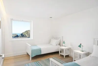 a white bedroom with a bed and a window at Shore Edge in Portreath