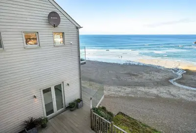 a house with a balcony looking at the beach at Shore Edge in Portreath