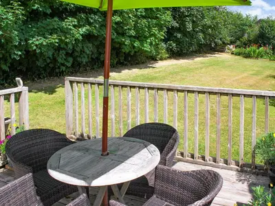 a table and chairs with an umbrella on a deck at Little Fursdon Apartment in Liskeard