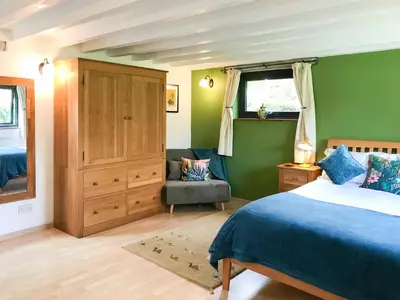 a bedroom with green walls and a bed and a chair at Little Fursdon Apartment in Liskeard