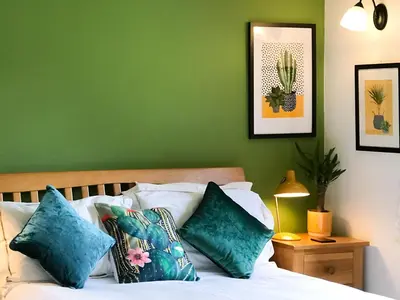 a bedroom with green walls and a bed with pillows at Little Fursdon Apartment in Liskeard